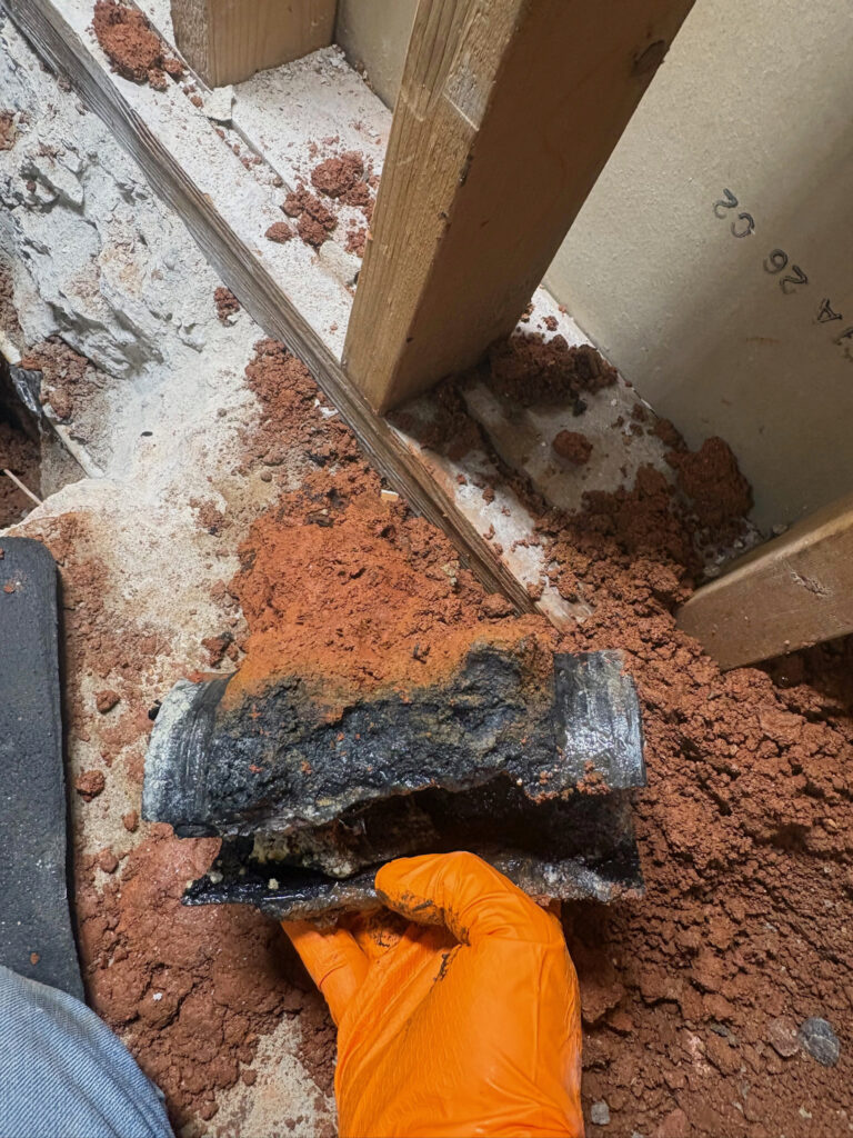 Freedom Plumbing client-provided photo of a damaged pipe section during an interior plumbing repair
