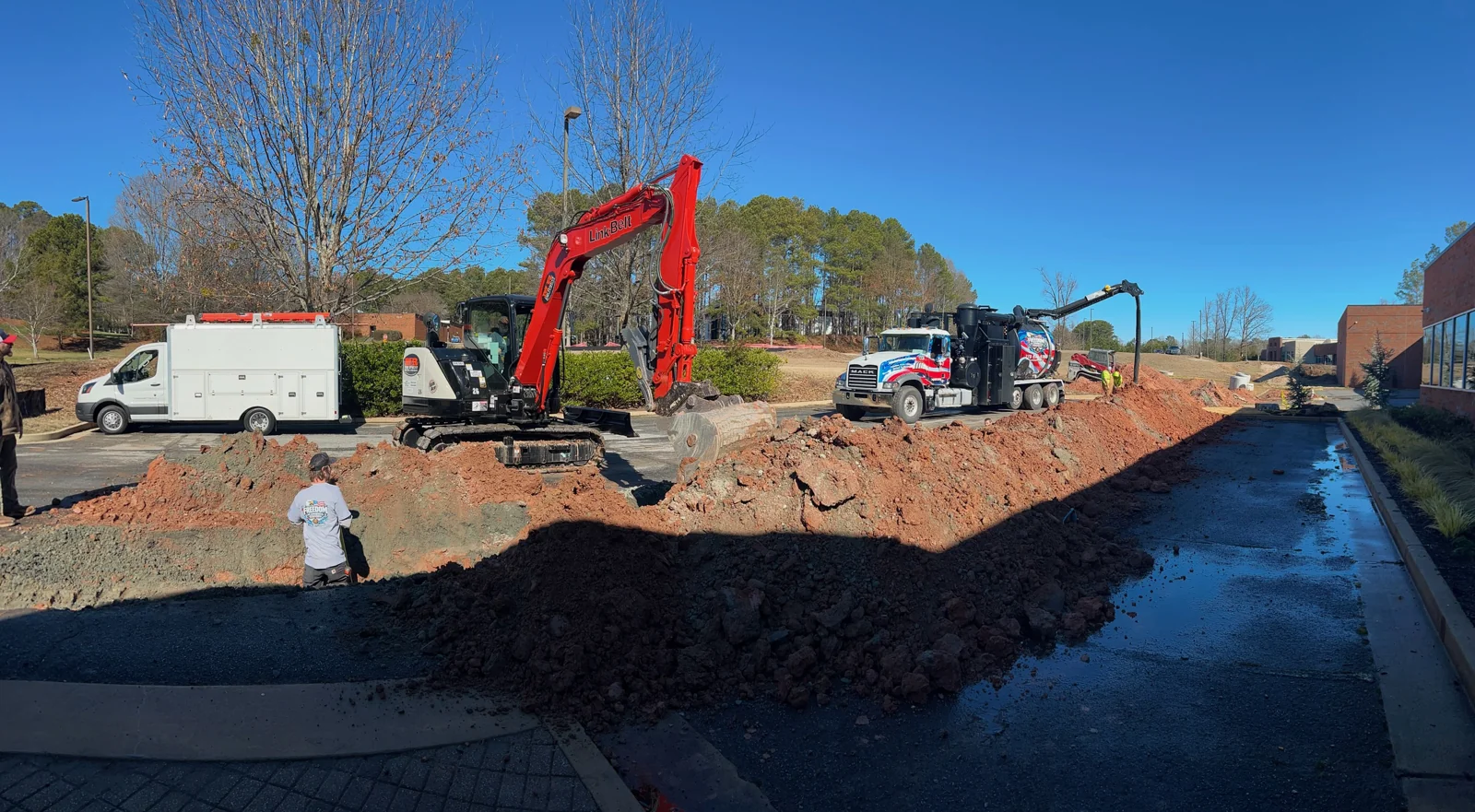 Service vehicles and excavation equipment at an outdoor work area.