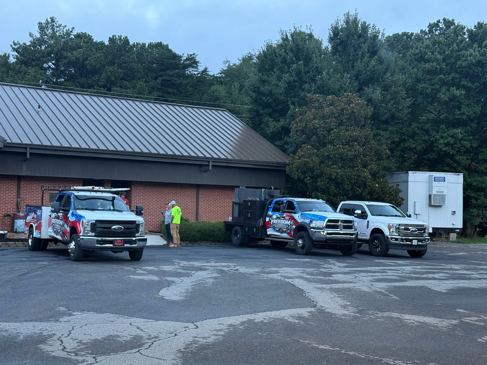 Freedom service vehicles parked beside a brick building.