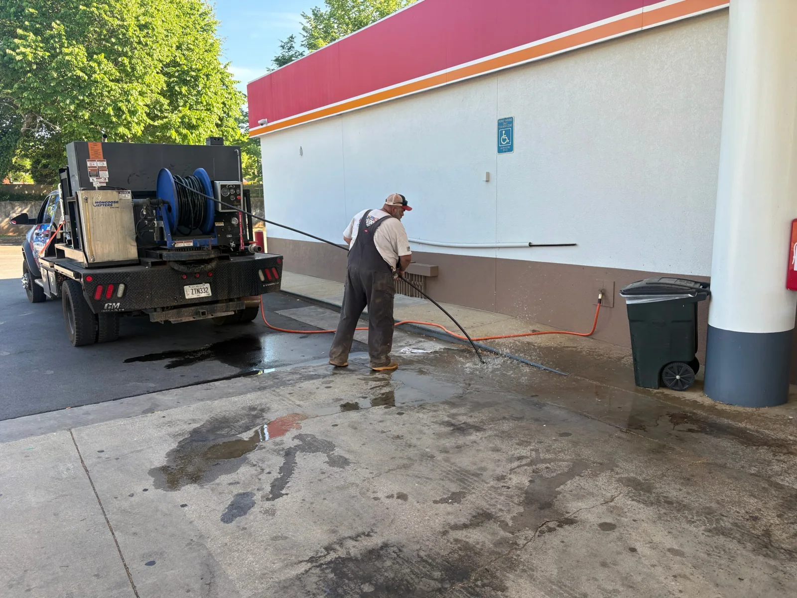 Person handling a hose beside a service truck with a hose reel.