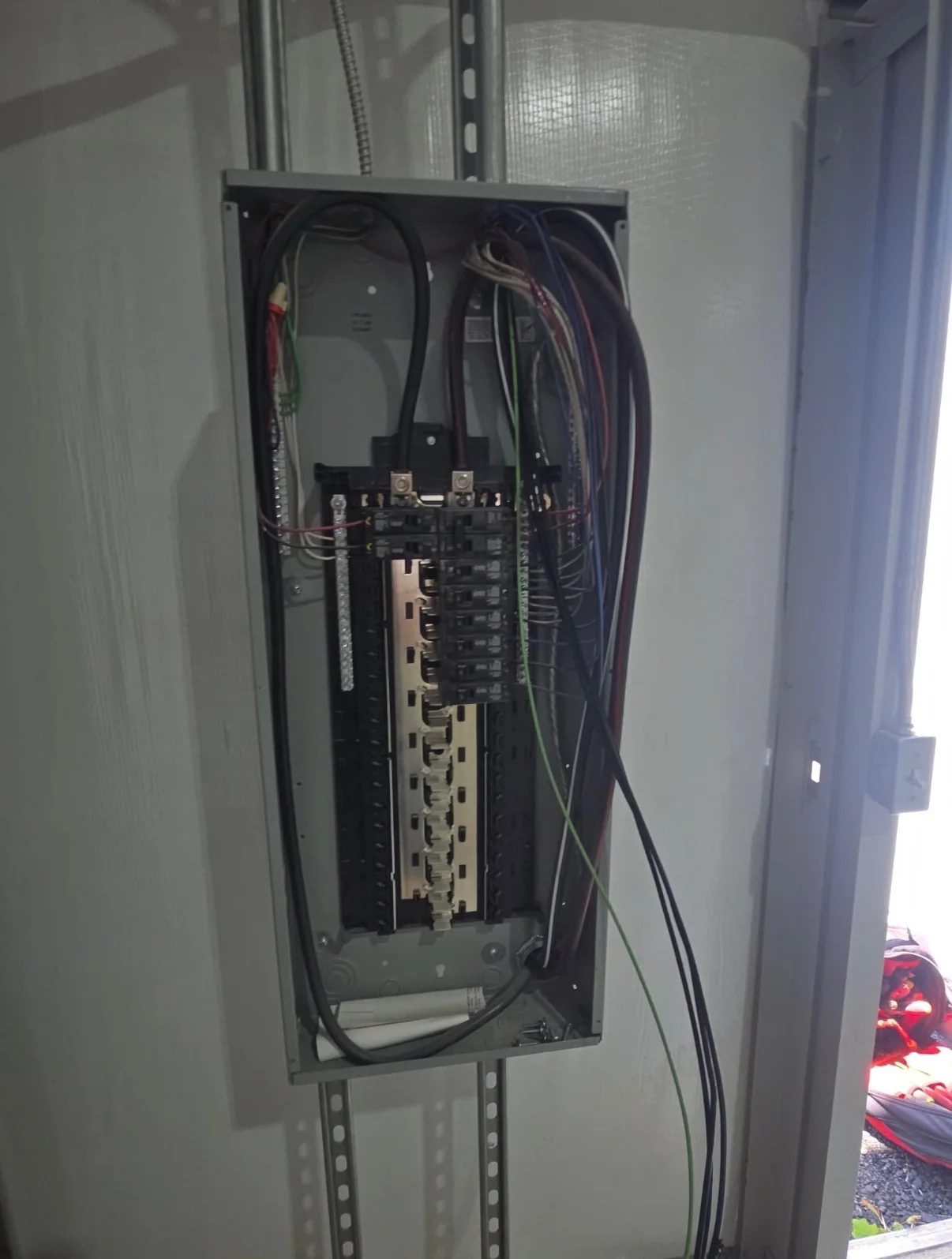 Open electrical breaker panel with wiring and breakers.